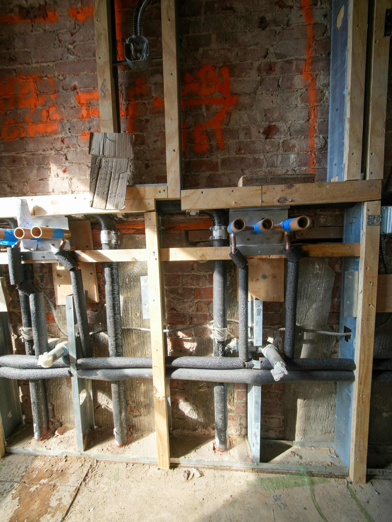 Exposed plumbing and framing in an open wall during a renovation